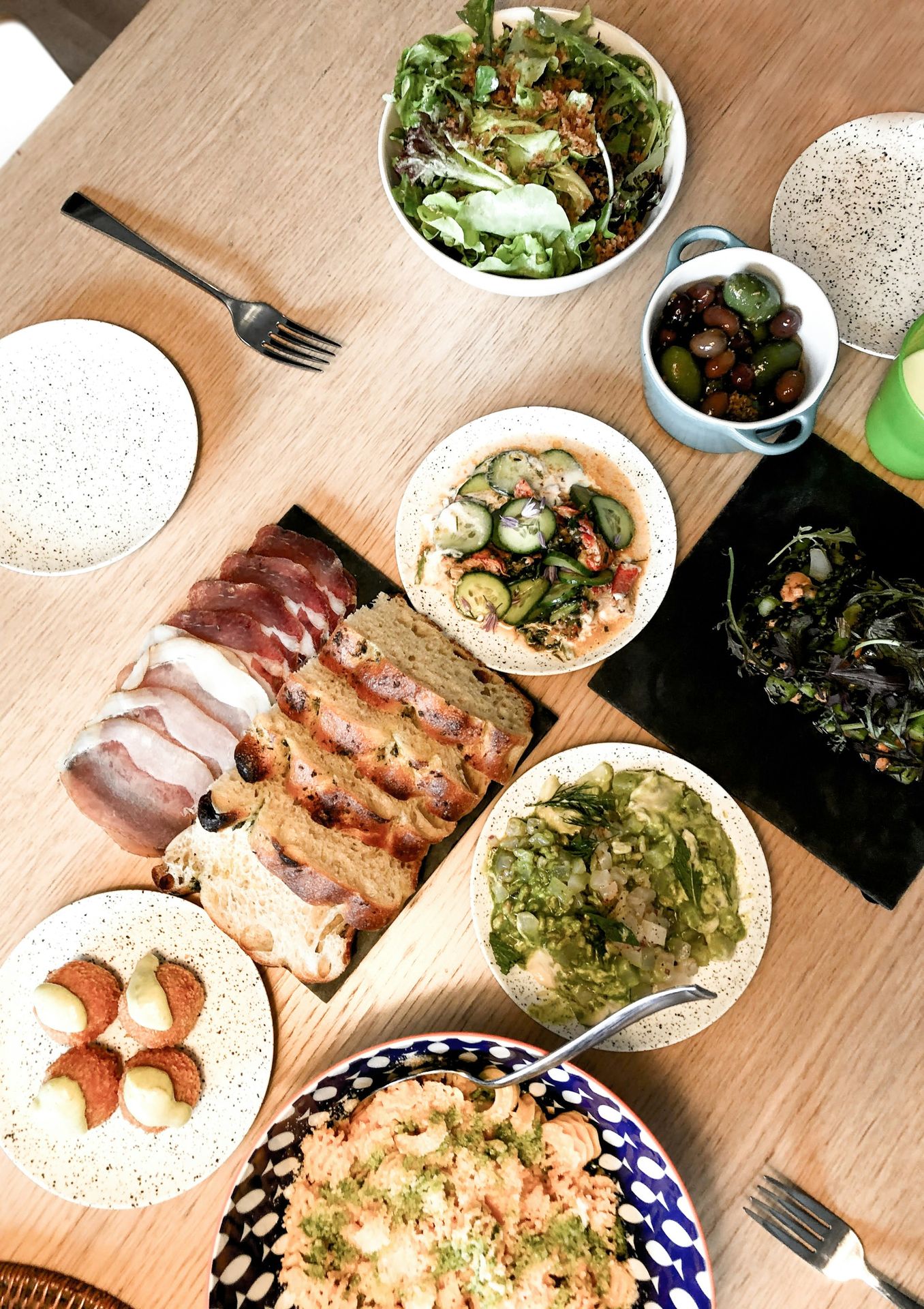 sliced meat on white ceramic plate beside green vegetable salad on white ceramic bowl